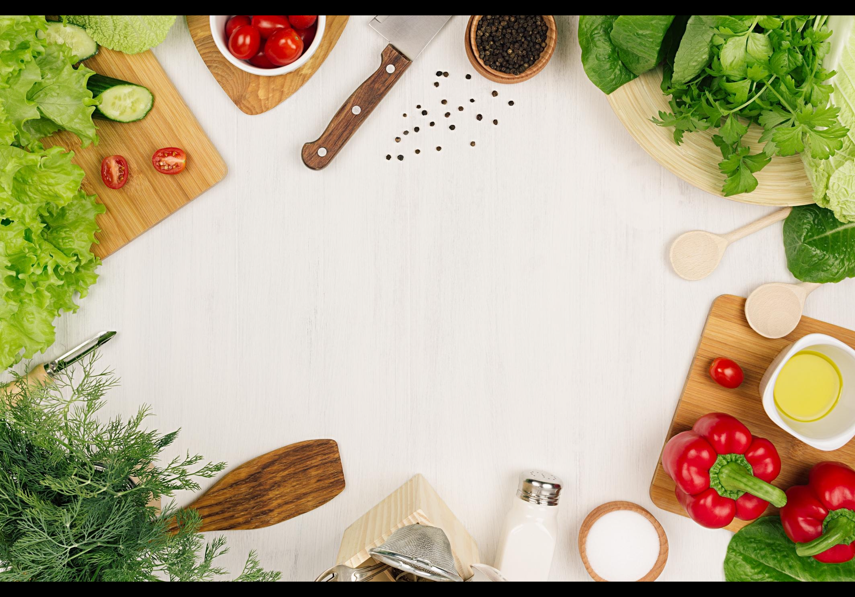 Assorted fresh vegetables, herbs, and wooden cooking utensils framing a blank white wooden surface.